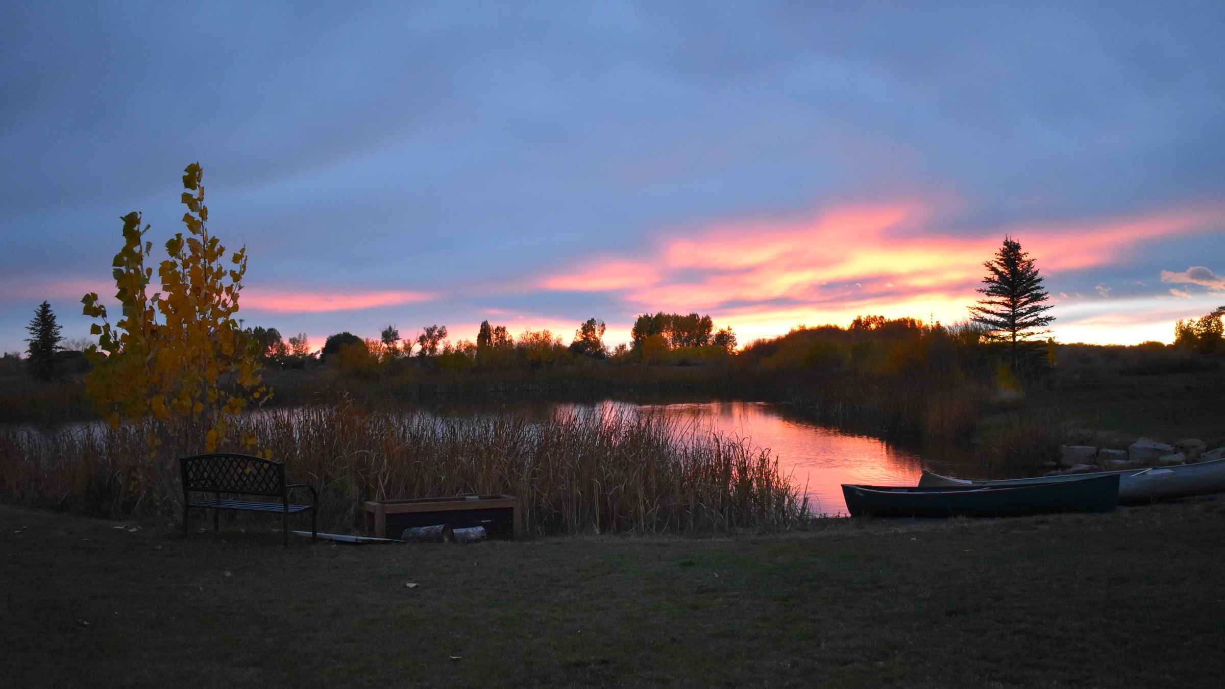 Canoes on the grass beside the private pond at Three Peaks Lodge