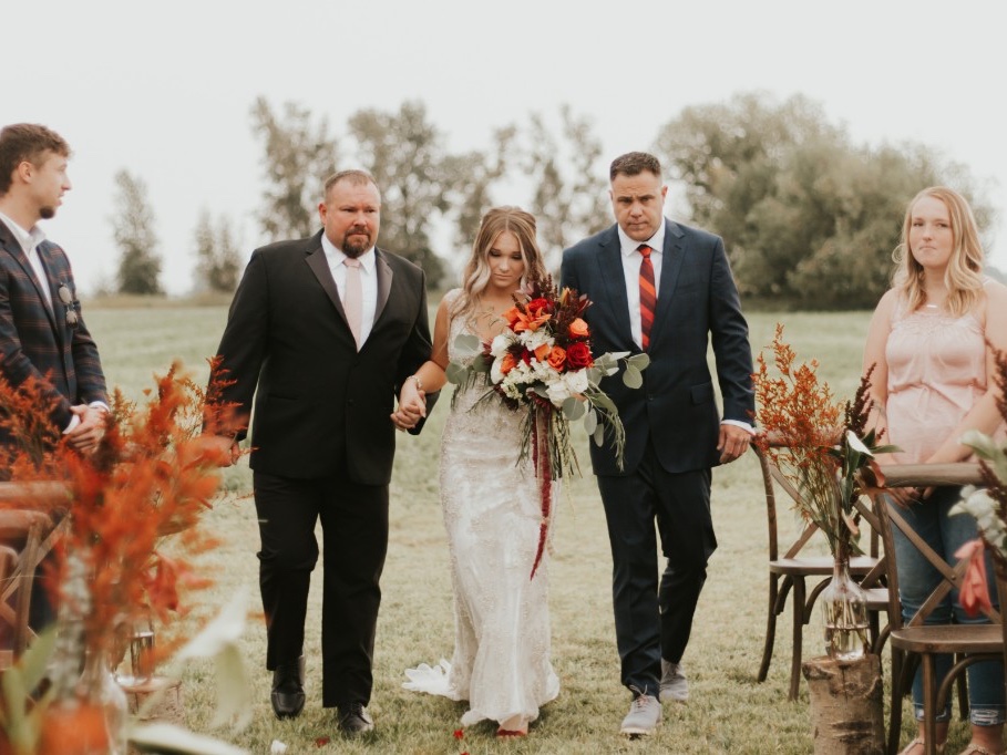 Bride walking the meadow aisle with her parents