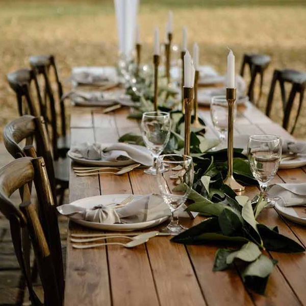 Outdoor farm table with greenery, taper candles, and place settings
